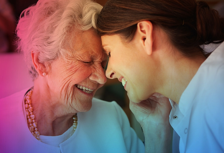 Elderly woman and younger woman smiling and being affectionate.